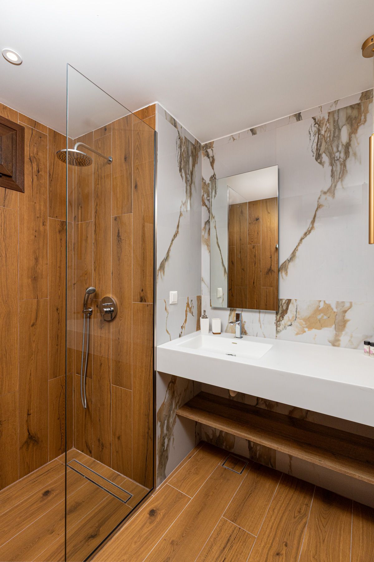 Anemoessa's bathroom, with a marble wall and an oak shower enclosure