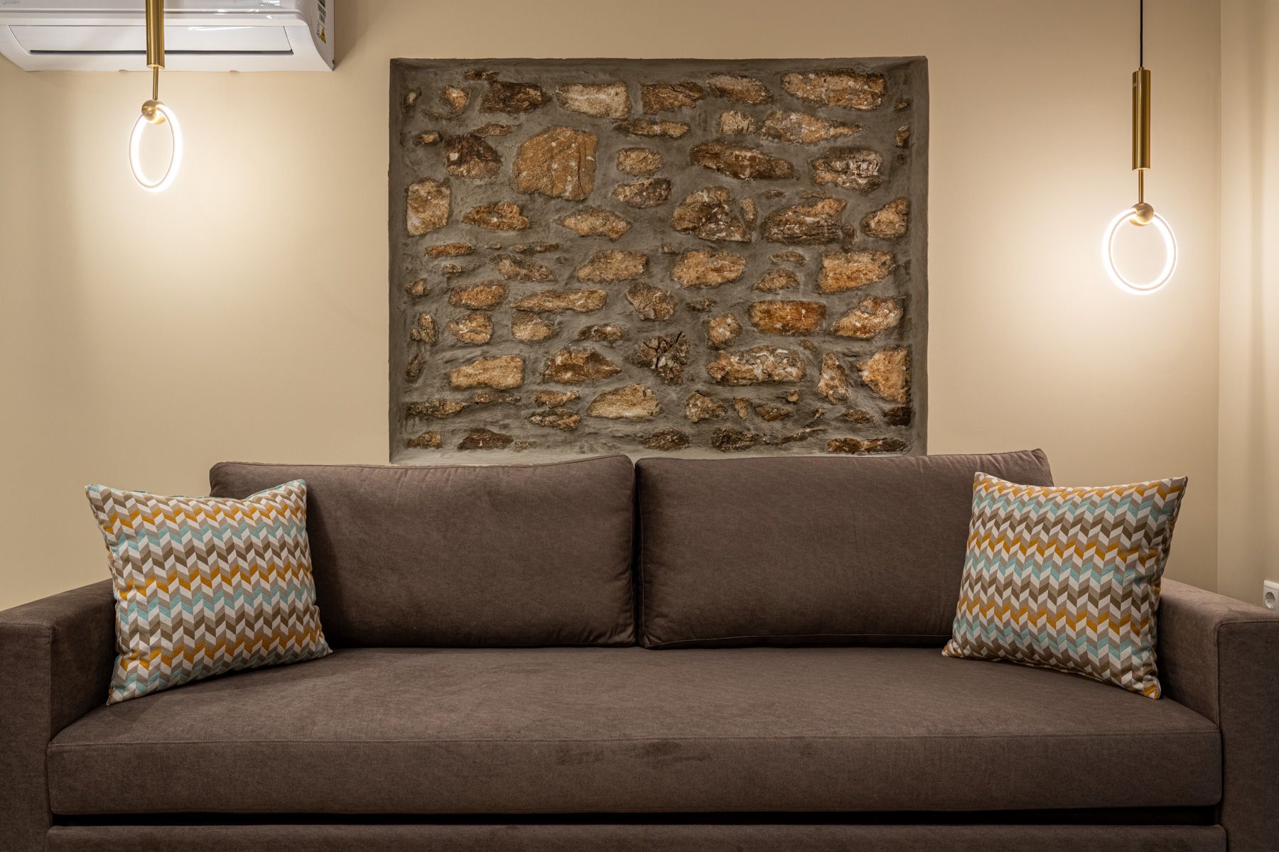 The three-seat sofa in Asteroessa, set against a panel of the house's original stone