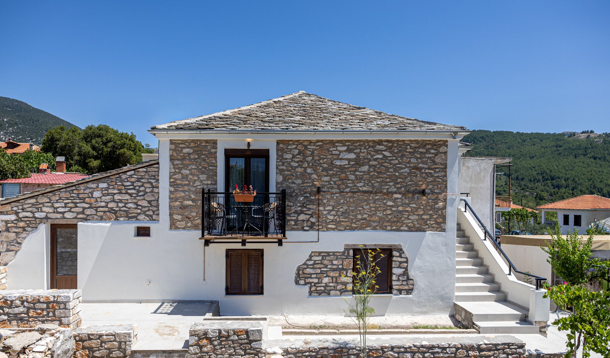 The front of the house in daylight, with the external stair to the upper suite
